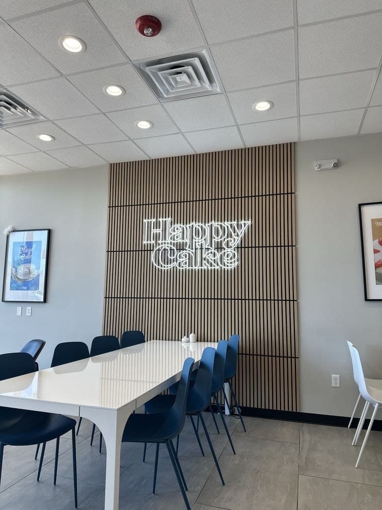 Inside HappyCake on Promenade Way — the long blue-chair table under our neon sign